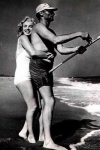 Arthur Miller pescando mientras Marilyn Monroe lo abraza